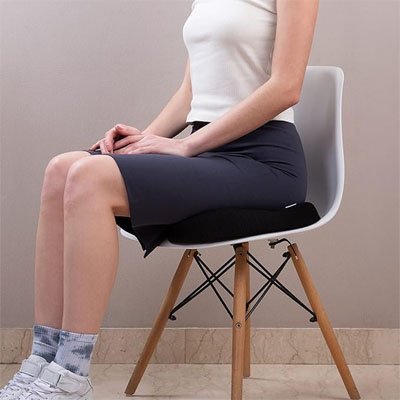 coussin ergonomique comfort noir sur chaise avec femme assise